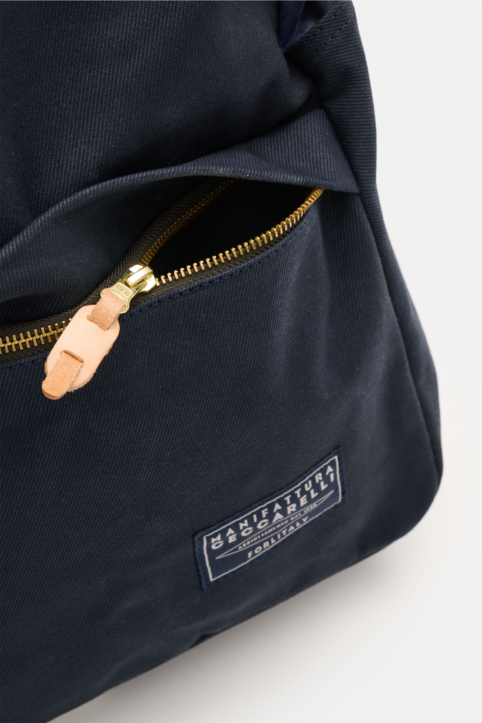 Nahaufnahme des Manifattura Ceccarelli Rucksack 'Laptop' navy von vorne rechts, reine Baumwolle, goldfarbener Reißverschluss und Logo-Patch.