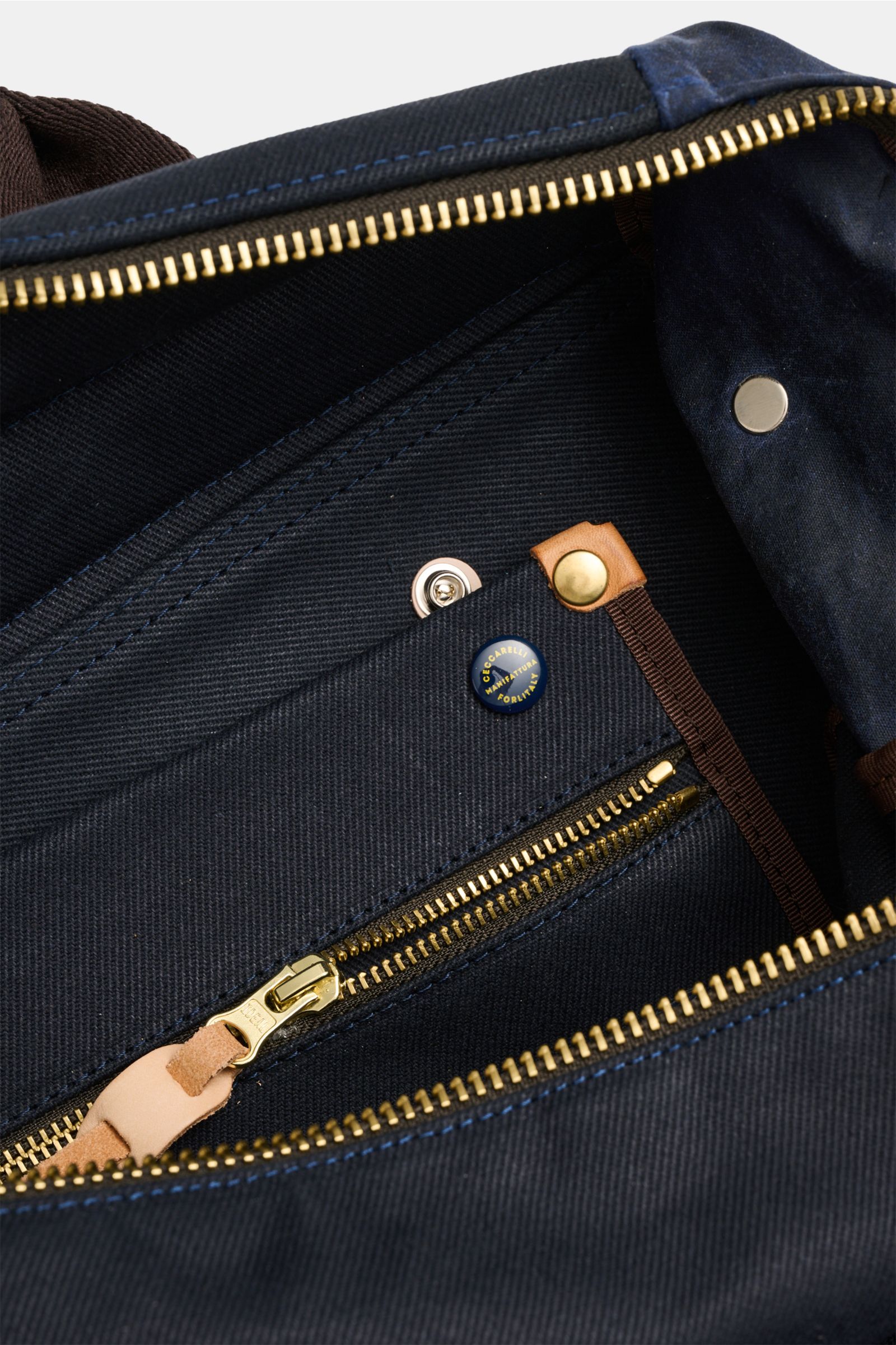 Manifattura Ceccarelli Rucksack 'Laptop' navy aus reiner Baumwolle, Detailansicht des geöffneten Innenfachs mit goldfarbenem Reißverschluss und Logo-Patch.
