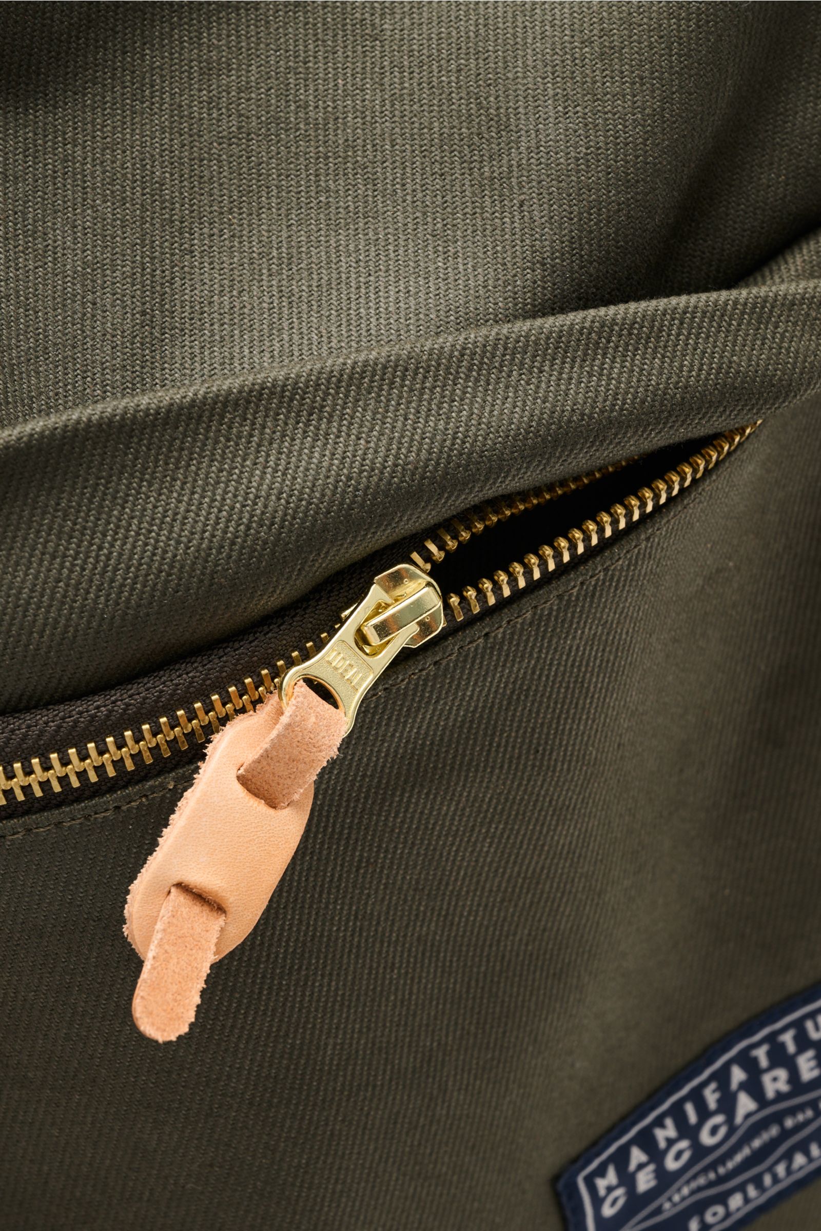 Nahaufnahme des olivgrünen Manifattura Ceccarelli Rucksack 'Laptop' mit goldfarbenem Reißverschluss, Leder-Zipper und Logo-Patch, reine Baumwolle.