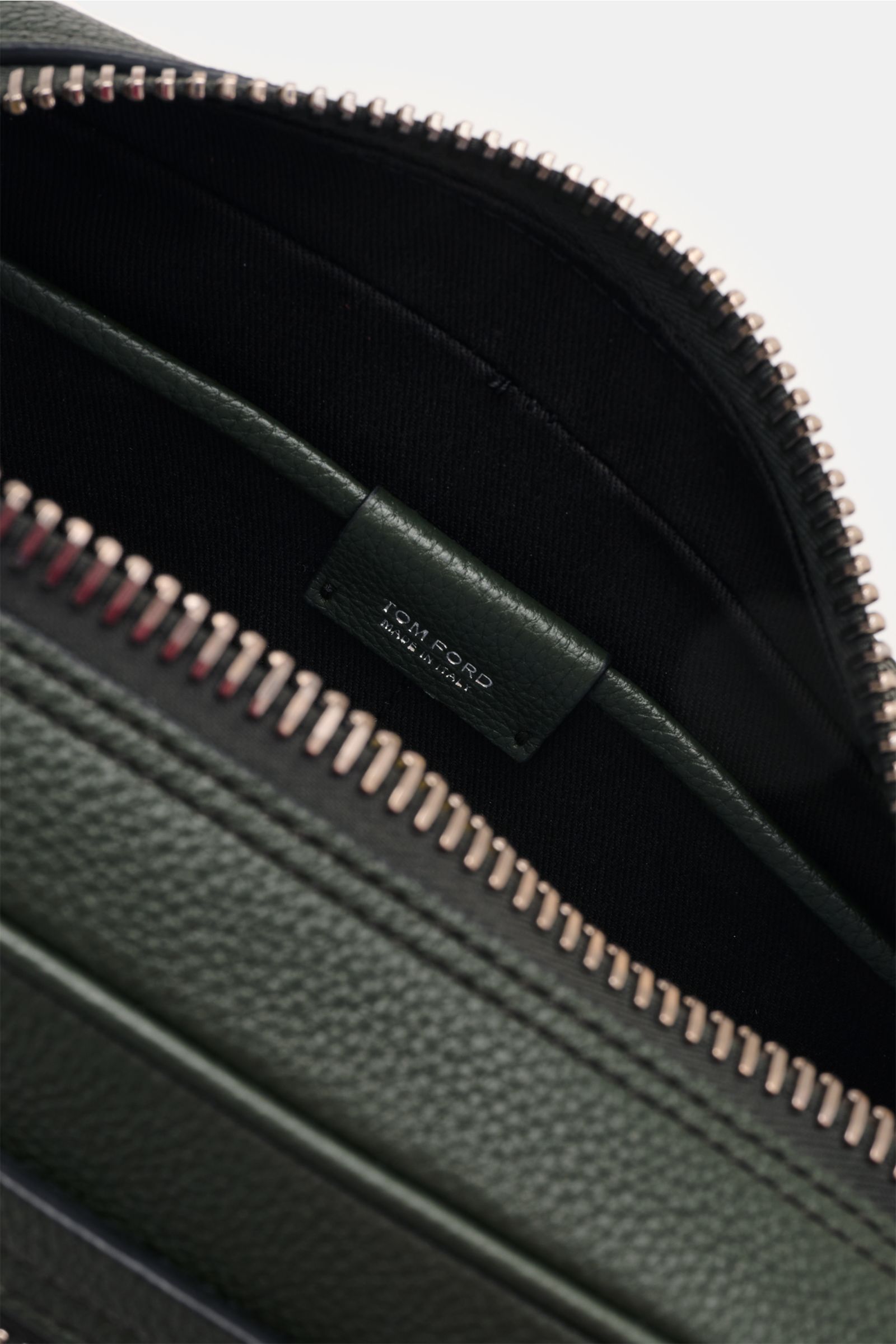 Close-up view of the interior of the Tom Ford Necessaire dunkelgrün, showing textured dark green calf leather and silver zipper.

Dieses edle Necessaire von 
