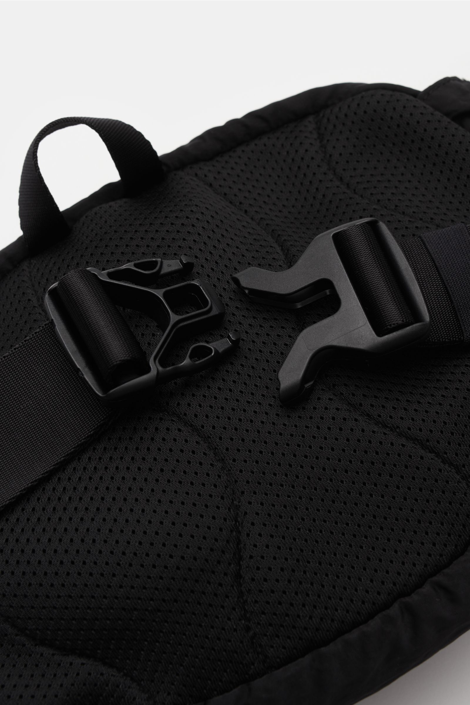Close-up view of the padded back of the C.P. Company Belt bag black, showing the adjustable strap with robust clip buckle and carry loop. Don’t go on trips or into the city without this compact, piece-dyed belt bag made of water repellent microfibre by C.