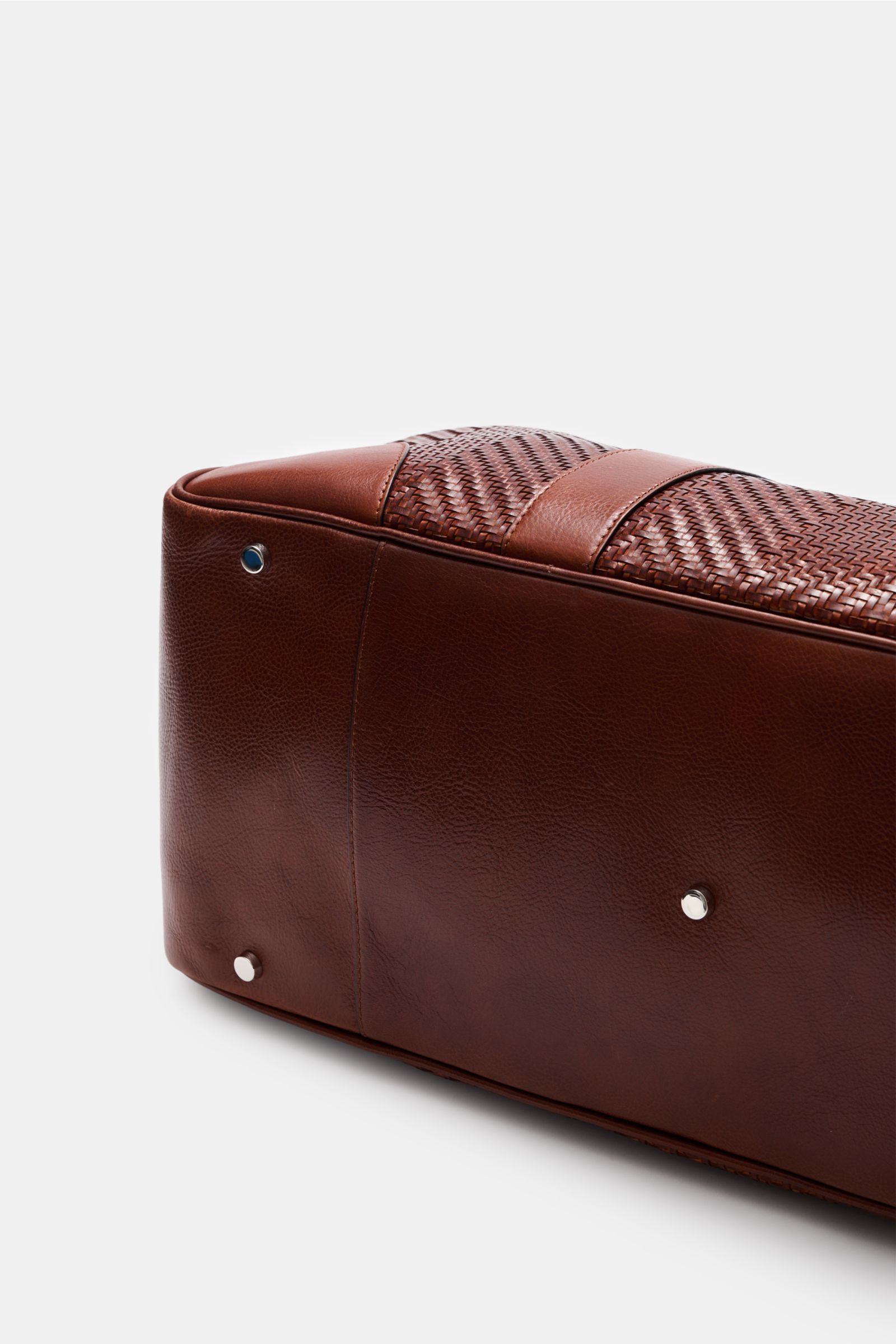 Brunello Cucinelli Weekender bordeaux shown from a close-up side-bottom angle, highlighting grainy calf leather, gold hardware, and metal feet. Ein praktisches Accessoire in exquisiter Lederqualität: Ein geräumiges Innenfach und die verstellbare Leders