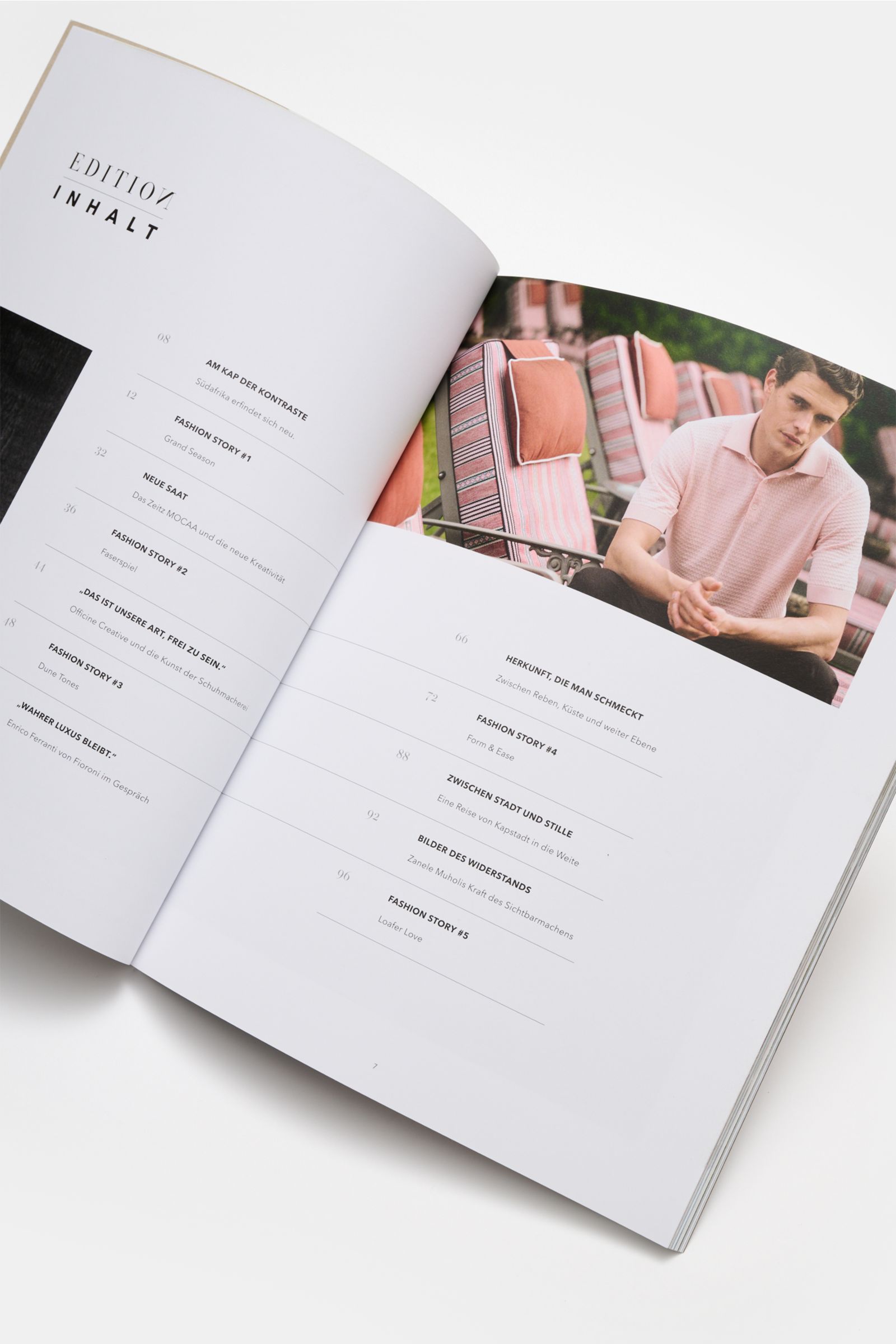 Edition EDITION Magazin Frühling 2026, schräg von oben fotografiert, zeigt geöffnete Inhaltsseite mit Text und Foto eines Mannes in rosafarbenem Polo.