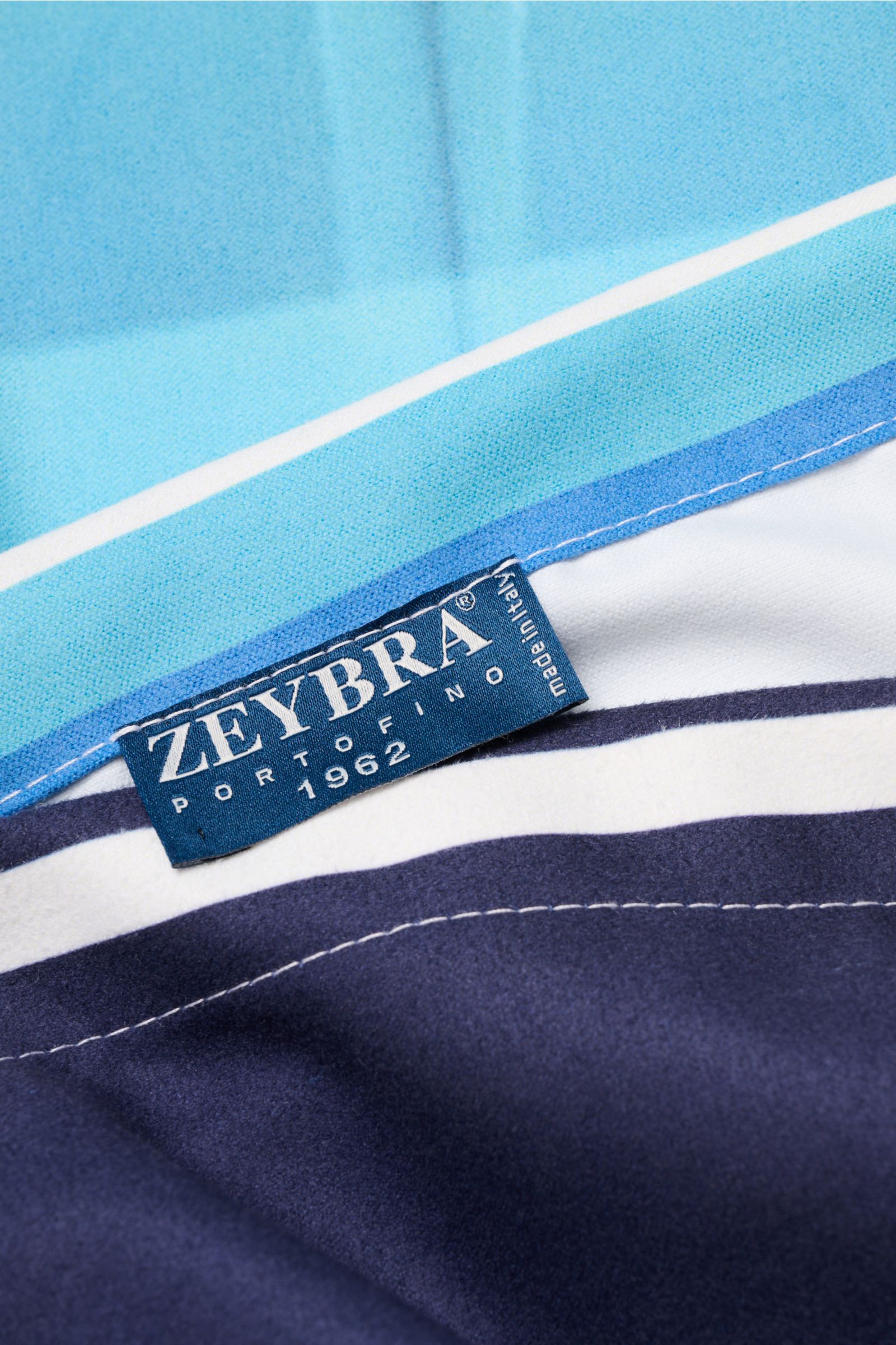 Nahaufnahme des Zeybra Portofino 1962 Strandtuchs blau/multicolor gemustert von schräg oben, feine Microfaser, glatter Griff, All-Over-Print mit Auto.