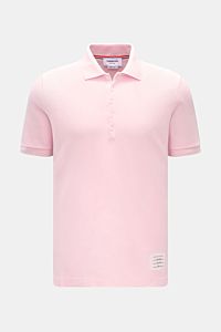 Thom Browne Poloshirt rosé, frontal fotografiert, Slim Fit aus reiner Baumwolle mit klassischem Polokragen, Fünf-Knopf-Leiste, Rippbündchen, elastischen Seiteneinsätzen und markentypischem Streifen-Logo.