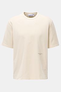 Stone Island Rundhals-T-Shirt 'Marina' creme shown from the front, oversized fit with a soft, heavy cotton fabric, round neckline, contrast ribbed shoulder detail, and subtle logo print on the front. Legeres Urlaubs-Essential: Das T-Shirt aus der STONE