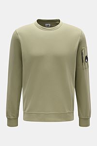 Front view of C.P. Company Sweatshirt oliv in light olive, slim fit round neck with garment dyed cotton, arm zipper pocket with lens detail, ribbed cuffs.