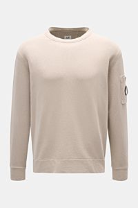 C.P. Company Rundhals-Sweatshirt beige shown from the front, made of garment-dyed pure cotton with a round neck, arm pocket, and ribbed cuffs. 