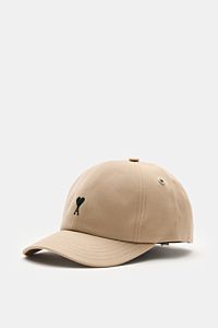 Ami Paris Baseball-Cap beige aus reiner Baumwolle, weicher Griff, gebogener Schirm, schwarzes Herz-Logo vorne, verstellbarer Verschluss, seitlich fotografiert.