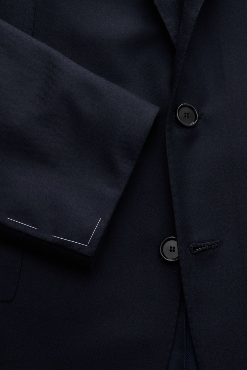 Nahaufnahme des Cesare Attolini Anzug dark navy aus Super 150'S Wolle, zeigt tailliertes Sakko mit drei Knöpfen und Ärmelabschluss.