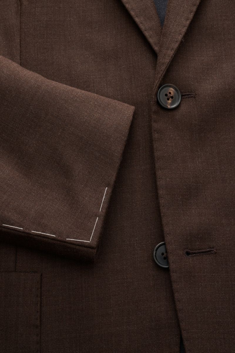 Nahaufnahme von einem Corneliani Sakko dunkelbraun meliert aus Schurwolle und Seide, Slim Fit, tailliert, Zwei-Knopf-Stil, fallendes Revers, klassische Brusttasche, aufgesetzte Hüfttaschen, Ärmelabschlüsse unfertig, rückwärtige Seitenschlitze, Unconstruct