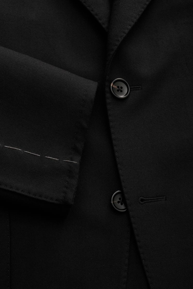 Nahaufnahme des Tom Ford Sakko 'Dylan' schwarz aus feinem Twill, Wolle mit Seide, Slim Fit, tailliert, zwei Knöpfe, fallendes Revers, Brusttasche, Hüfttaschen, unfertige Ärmel, Seitenschlitze, halb gefüttert, vier Innentaschen.