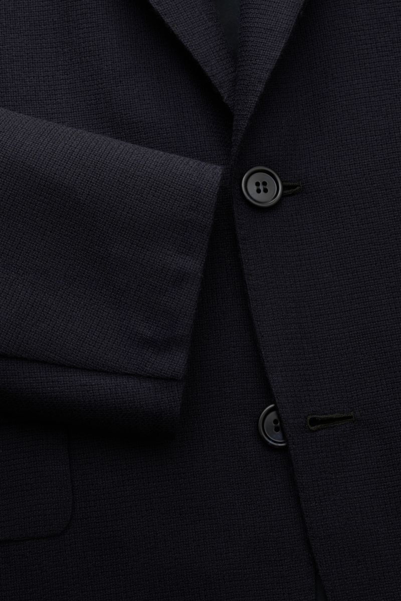 Close-up front view of the Brioni Smart-casual jacket 'New Plume' navy showing the pure cashmere fabric, slim fit, two-button style, step lapel, classic breast pocket, flap hip pockets, unfinished sleeve cuffs, and branded lining details. For smart office