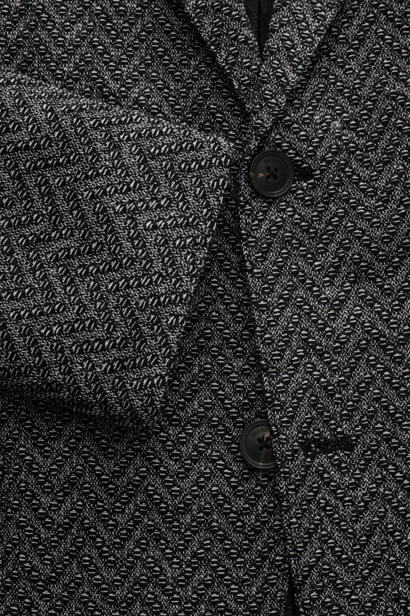 Close-up front view of the Emporio Armani Strickblazer schwarz/weiß gemustert, featuring a slim fit, two-button style, and zig-zag wool knit texture.

Edles Piece mit Twist von EMPORIO ARMANI: Mit diesem Blazer aus feinem und leichtem Strukturstrick au