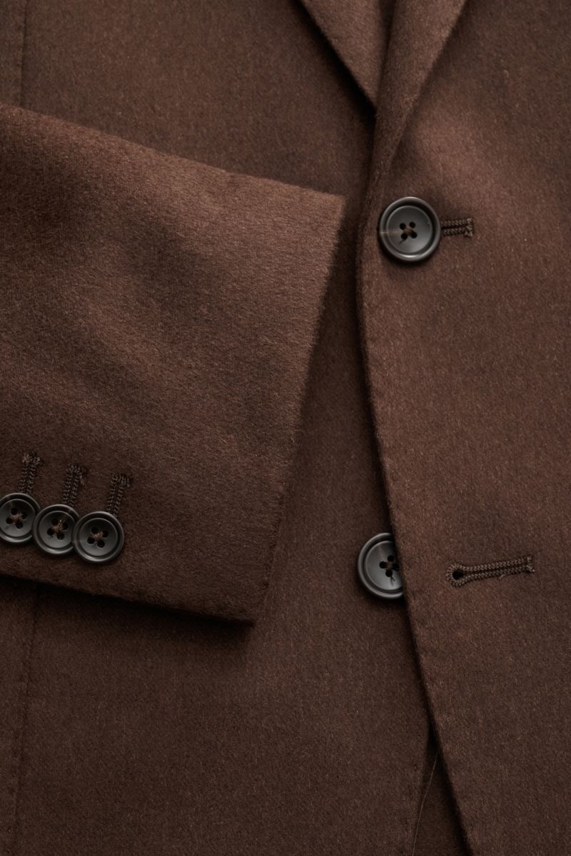 Nahaufnahme des dunkelbraunen Tagliatore Kamelhaar Sakkos 'Monte Carlo' mit Unconstructed-Verarbeitung, Slim Fit, tailliertem Zwei-Knopf-Stil, fallendem Revers und Kissing Buttons.