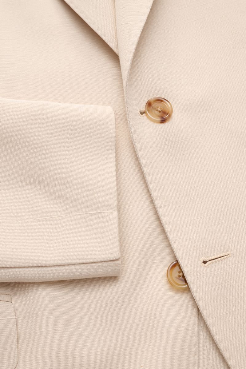 Lardini Sakko sand, Nahaufnahme von Ärmel, Revers und zwei braunen Knöpfen aus Viskose-Seiden-Mix, leichte Struktur, Slim Fit, tailliert, von oben fotografiert.