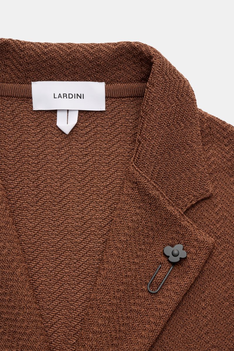 Nahaufnahme des braunen Lardini Strickblazers mit Fischgratmuster, fallendem Revers, Blütenpin, aus Baumwoll-Viskose, aus frontaler Perspektive.