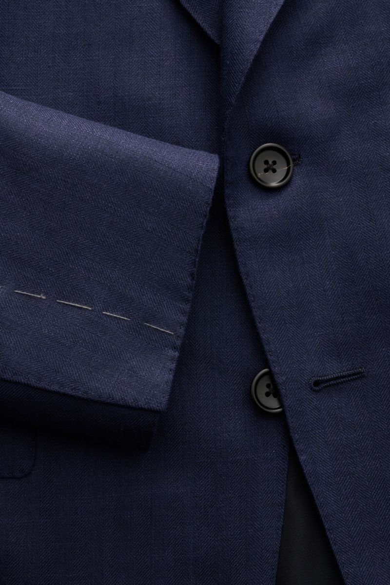 Close-up front view of the Tom Ford Sakko 'Shelton' navy jacket showing its two black buttons, soft wool-silk-linen blend with subtle herringbone pattern, slim fit, and unfinished sleeve hems. Für den souveränen Auftritt: Das Sakko 'Shelton' von TOM FO