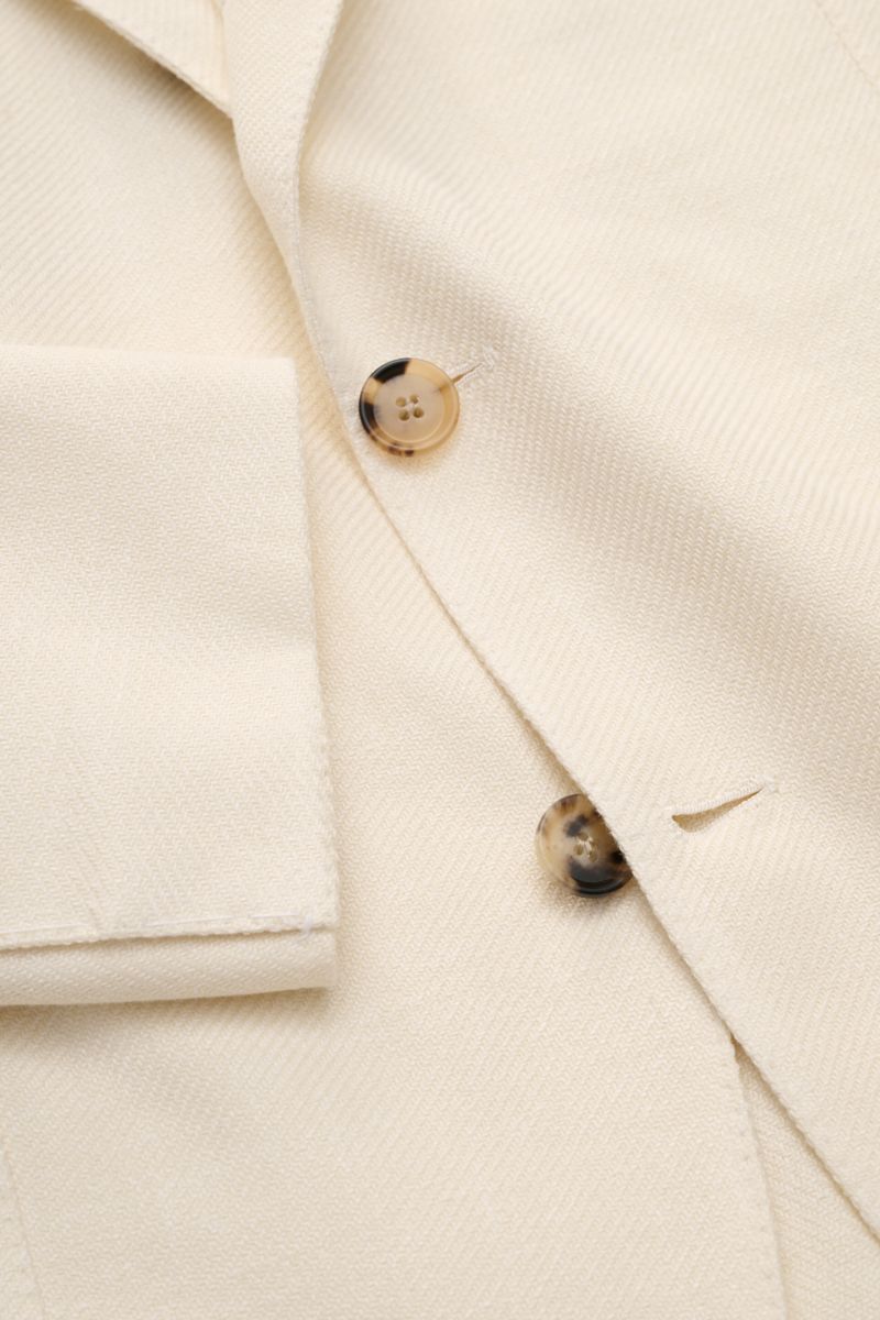 Close-up top view of Borrelli Smart-casual jacket 'Procida' cream showing texture, buttons, and lapel detail.

Description: Business elegance in a summery design: With its lightweight material and exceptional feel, the smart-casual jacket 'Procida' by 