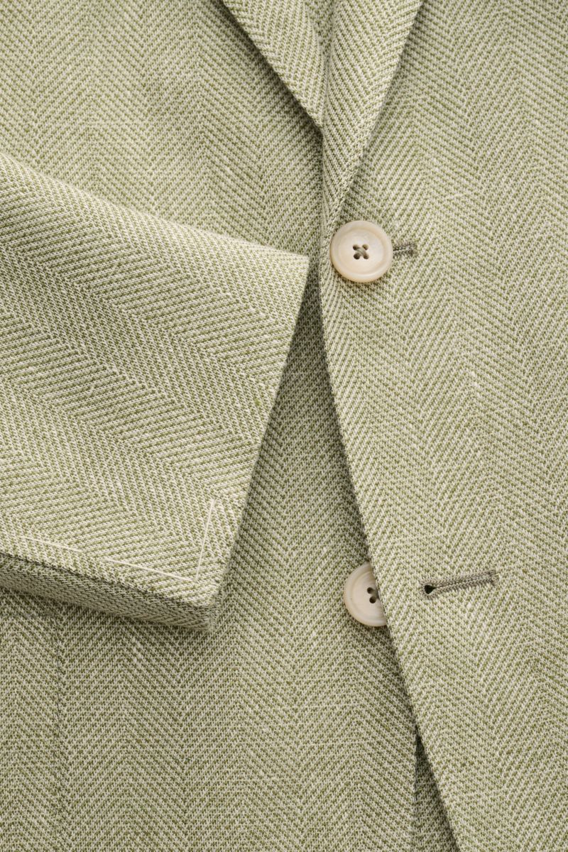 Nahaufnahme des Tagliatore Sakko 'Monte Carlo' oliv meliert mit Fischgrat-Struktur, zwei Knöpfen und unfertigen Ärmelabschlüssen.