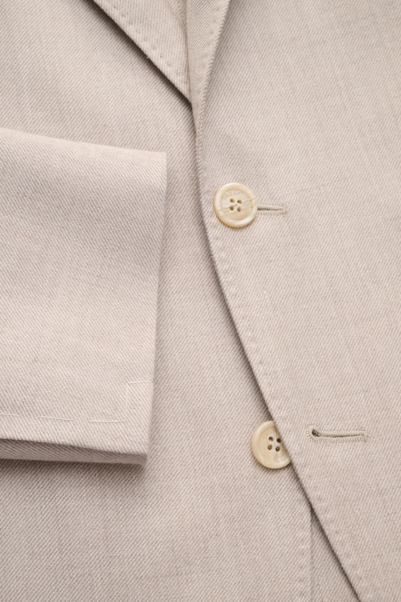 Brunello Cucinelli Sakko sand meliert, Nahaufnahme von Knöpfen, fallendem Revers, tailliertem Drei-Knopf-Stil, weichem Cashmere-Seide-Mix, markanter Webstruktur.