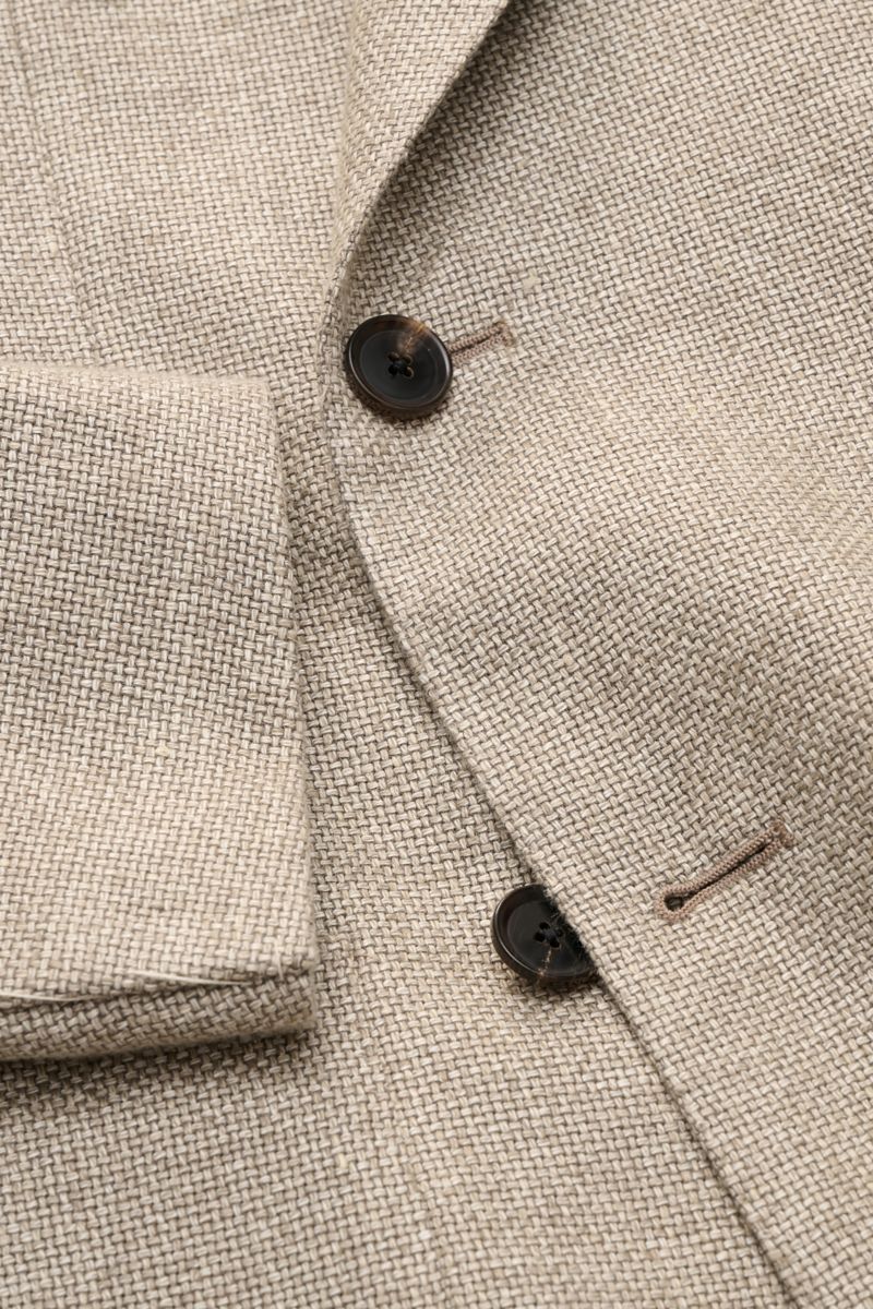 Nahaufnahme des Caruso Sakko 'Aida' beige meliert im rustikalen italienischen Stil mit markanter Hanf-Woll-Webstruktur, steigendem Spitzrevers und zwei braunen Knöpfen, fotografiert von oben.