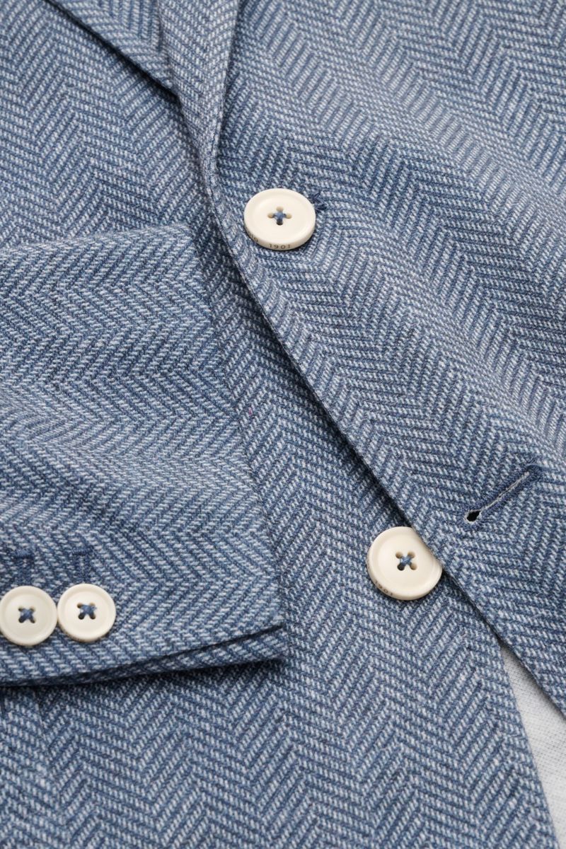 Nahaufnahme des Circolo 1901 Jersey-Sakkos rauchblau/weiß gemustert mit Fischgrat-Muster, Knöpfen und Brusttasche, Perspektive von oben.