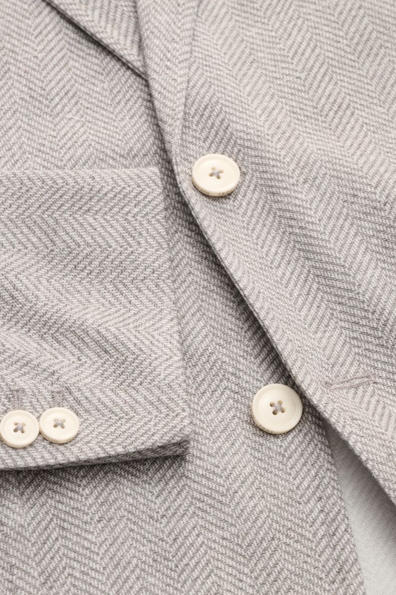 Close-up image from a top-front perspective of a Circolo 1901 Jersey smart-casual jacket grey/off-white patterned, showing herringbone texture, cream buttons, breast and patch hip pockets, and buttoned cuffs.

Casual elegance for warm days: This smart-