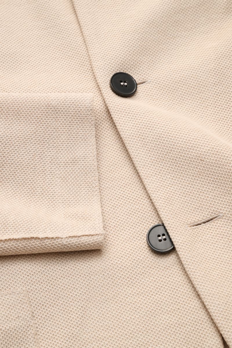 Close-up top view of Harris Wharf London Knit blazer beige showing pure piqué cotton fabric, black buttons, and patch pocket detail. 

Description: HARRIS WHARF LONDON has chosen a high-quality cloth from Loro Piana for this relaxed knit blazer. Pure c