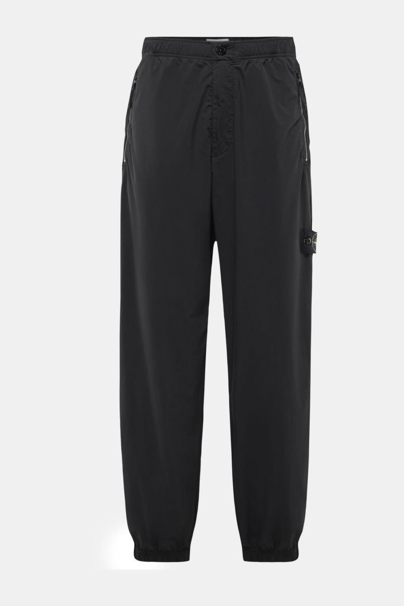 Stone Island Jogger pants black shown from the front, made of high-quality microfibre with a regular fit, tapered cut, zip pockets, elasticated cuffs, and a partially elasticated waistband with internal drawstring; designed for sporty, relaxed spring casu