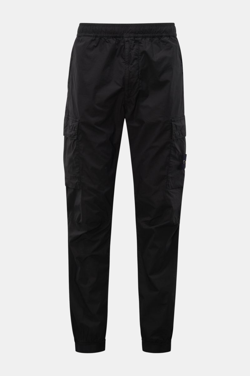 Front view of Stone Island Cargo-Jogpants 'Regular Tapered' schwarz in black cotton with stretch, featuring elastic waistband, zip pockets, cargo pockets, compass badge, knee darts, back button pocket, and elastic cuffs. For those who want function and st