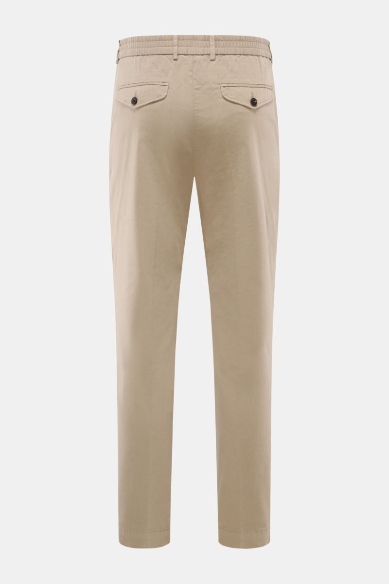 Rückansicht der taupefarbenen 04651/ A trip in a bag Baumwoll-Jogpants 'Flex Light' mit kurzem, sehr schmal zulaufendem Schnitt, teilelastischem Bund, französischen Taschen und geknöpften Gesäßtaschen.