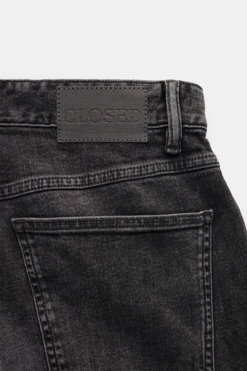 Closed Jeans 'Cooper' anthrazit mit Slim Fit, Five-Pocket-Stil, Zip Fly, Lederpatch und typischem CLOSED-Weblabel, Rückansicht nah.