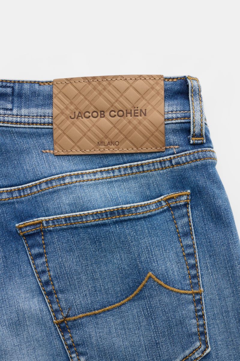Close-up rear view of Jacob Cohen Jeans 'Bard' blau showing blue denim with authentic used wash, detailed stitching, and a brown leather patch with logo. Modern luxury: premium jeans combining iconic style with high comfort, elastic cotton denim, soft tou
