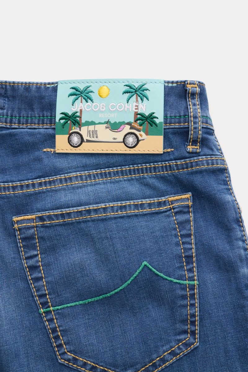 Jacob Cohen Jeans 'Bard' blau shown from the rear upper section, highlighting the back pocket with green stitching and a leather patch with car and palm trees. Premium-Denim from the Italian expert Jacob Cohen: The classic 'Bard' made of cotton with visco