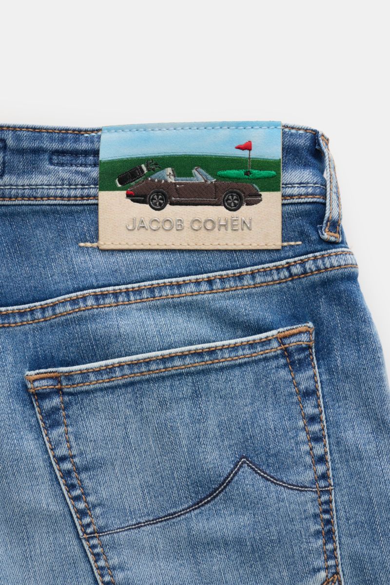 Close-up rear view of Jacob Cohen Jeans 'Bard' graublau showing soft, elastic cotton denim with subtle wash and a leather patch featuring a Porsche on a golf course.