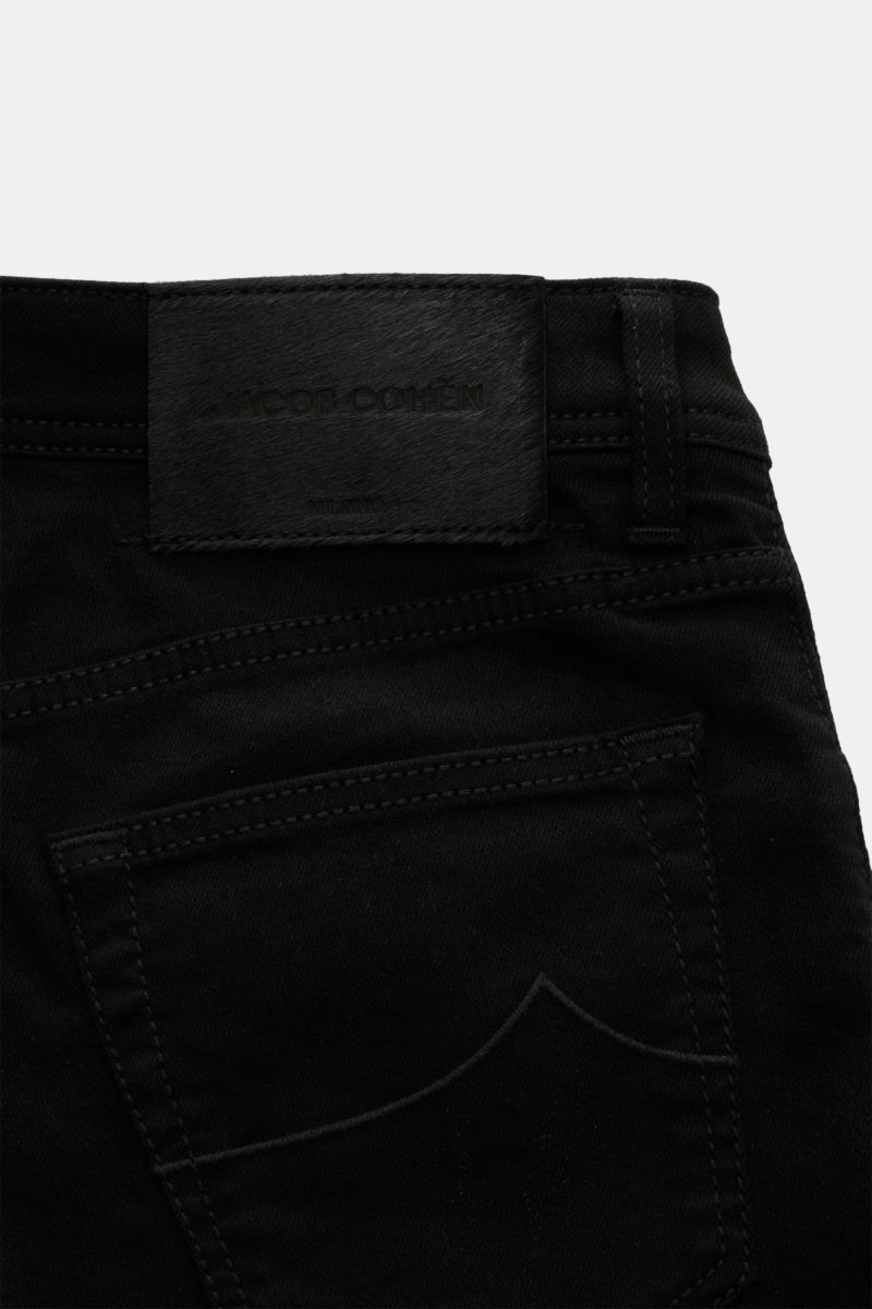Close-up rear view of Jacob Cohen Jeans 'Nick' black showing back pocket with stitching and leather patch in pony skin look. Denim made of cotton and microfibre, elasticated fabric, soft feel, slim fit, tapered cut, button fly, five-pocket style, coin poc