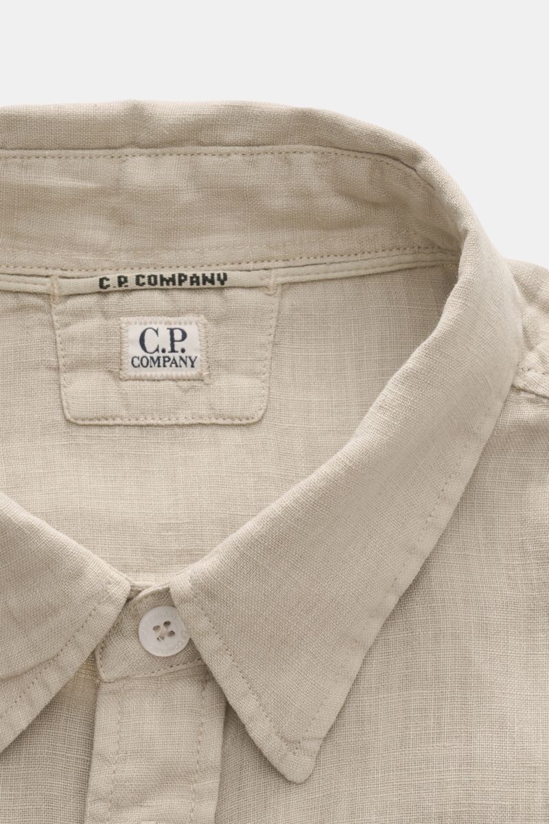 Close-up front top view of C.P. Company Linen shirt narrow collar sand, showing narrow collar, patch button placket, and linen texture. 