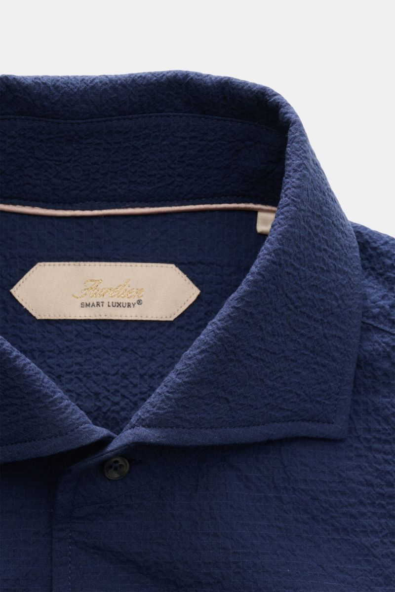 Aurélien Seersucker-Hemd Haifisch-Kragen dunkelblau shown close-up from above, highlighting textured cotton fabric and collar details.  
Sommerlicher Eyecatcher: Das Hemd von AURÉLIEN überzeugt mit charakteristischem Seersucker-Design und luftiger Mate