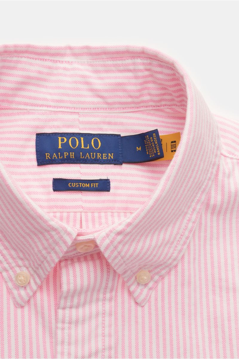 Close-up front view of Polo Ralph Lauren Oxfordhemd Button-Down-Kragen rosé/weiß gestreift, showing pink and white stripes, button-down collar, and brand label.

Zeitloser Allrounder: Das Oxford-Hemd von POLO RALPH LAUREN verbindet klassisches Streifen