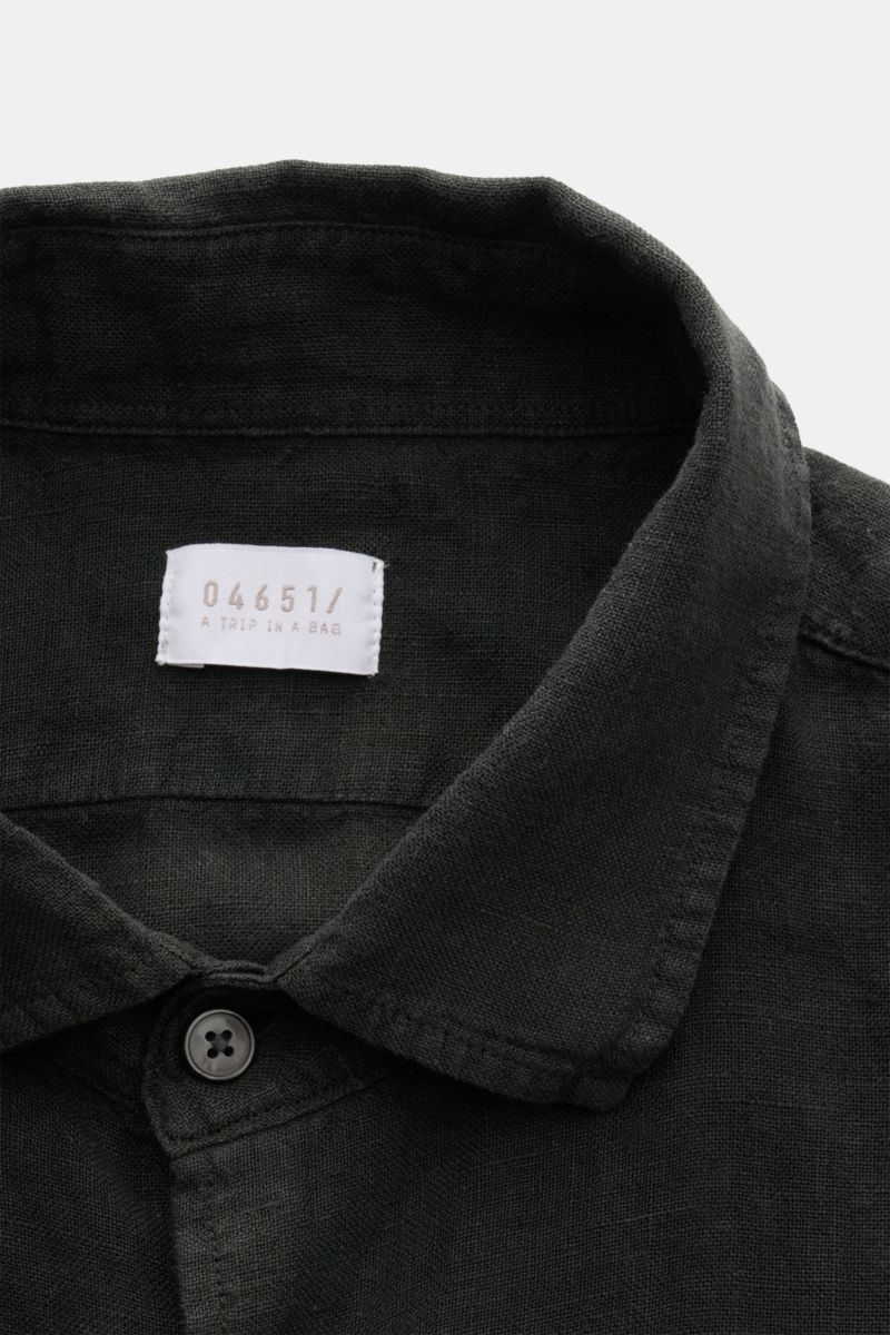 Close-up front view of the black 04651/ A trip in a bag Leinenhemd schmaler Kragen schwarz shirt collar and top button, showing fine linen texture. Mühelose Leichtigkeit