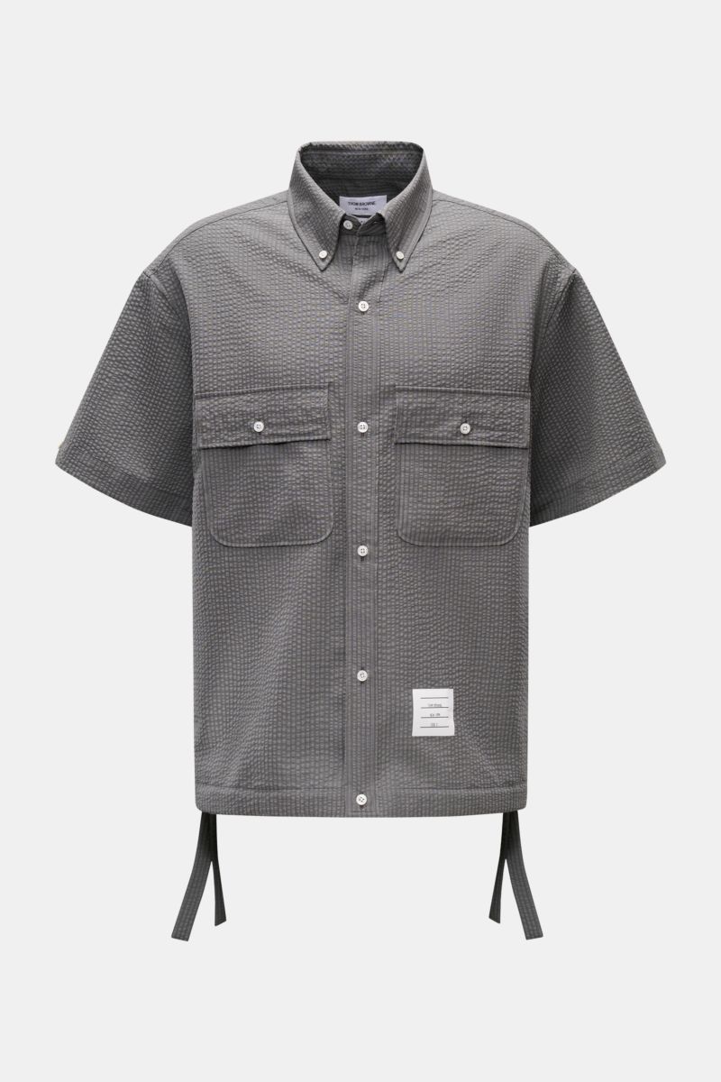 Thom Browne Seersucker-Kurzarmhemd Button-Down-Kragen dunkelgrau, oversized, strukturierter Wolle, Perlmuttknöpfe, Saum regulierbar, frontale Nahaufnahme.