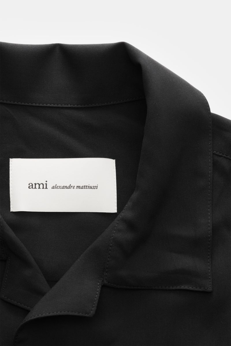 Close-up front top view of Ami Paris Short sleeve shirt 'Boxy' Cuban collar black showing soft pure viscose fabric and logo stitching.

Modern and casual: With its 'Boxy' fit, this short sleeve shirt by AMI PARIS is an uncomplicated key piece for sprin