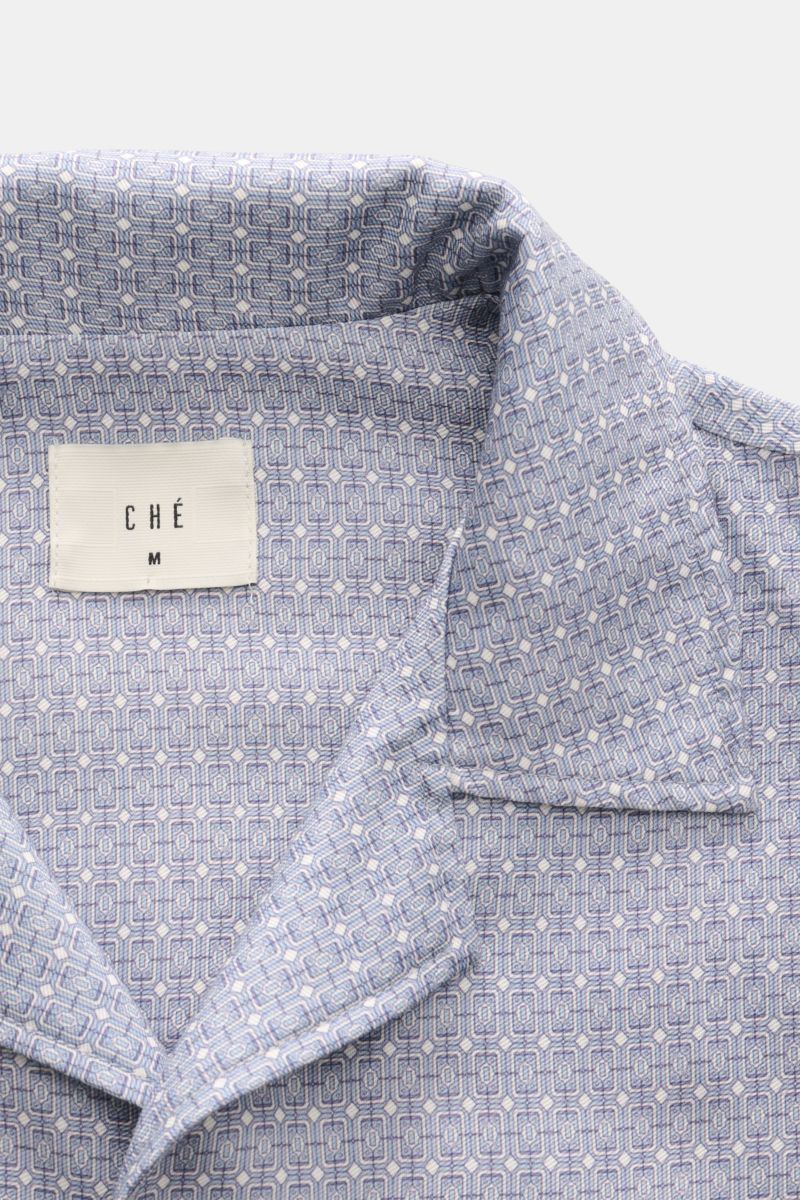 Ché Kurzarmhemd 'Lucena' Kubanischer Kragen rauchblau/offwhite gemustert, close-up front view showing ornamental print, collar, and fabric texture. Das Kurzarmhemd 'Lucena' von CHÉ zieht mit ornamentalem Print, fließendem Lyocell und entspannter Oversi