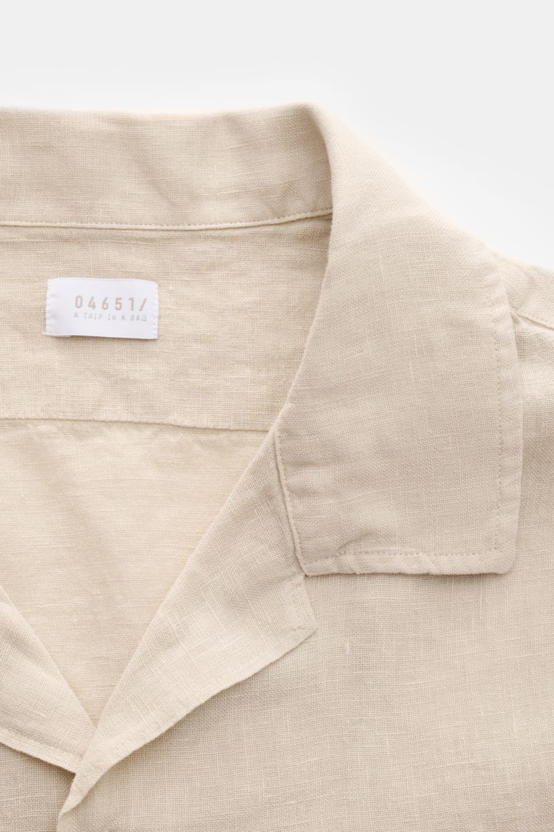 Detailaufnahme des beigen 04651/ A trip in a bag Leinen-Kurzarmhemd Kubanischer Kragen aus reiner Leinenqualität mit französischer Knopfleiste und feiner Struktur.