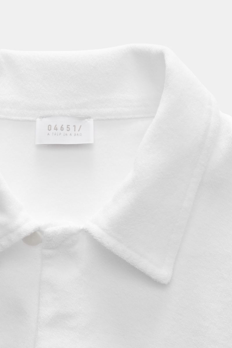 Close-up front view of the collar and label of the 04651/ A trip in a bag Frottee-Kurzarmhemd 'Terry Cuba' weiß made of soft pure cotton terry. Urlaubsgefühl zum Anziehen: Das Kurzarmhemd 'Terry Cuba' von 04651/ A TRIP IN A BAG aus angenehmem Baumwoll-Fro