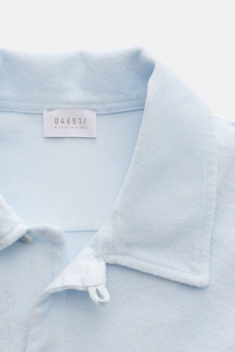 Close-up front view of the pastel blue 04651/ A trip in a bag Frottee-Kurzarmhemd 'Terry Cuba' shirt collar showing soft cotton terry fabric, regular fit, variable Cuban collar, French button placket, small side seam label, and short hem slits. Urlaubsgef