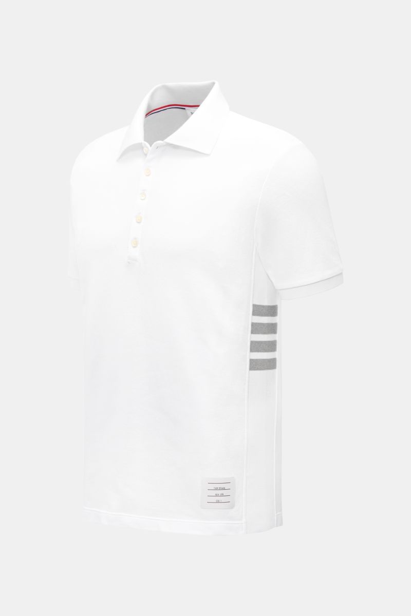 Front-side view of a slim fit Thom Browne Polo shirt white in pure cotton with a classic collar, five-button placket, ribbed cuffs, stretchy side inserts, and signature striped logo.

A modern essential: This polo shirt by THOM BROWNE is luxurious and 