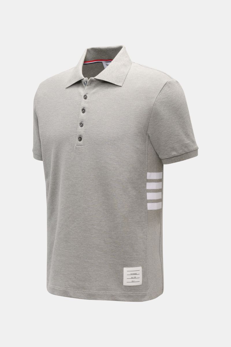 Front-right perspective of a slim fit Thom Browne Polo shirt grey mottled in pure cotton with a classic collar, five-button placket, ribbed cuffs, stretchy side inserts, and signature striped logo.

A modern essential: This polo shirt by THOM BROWNE is