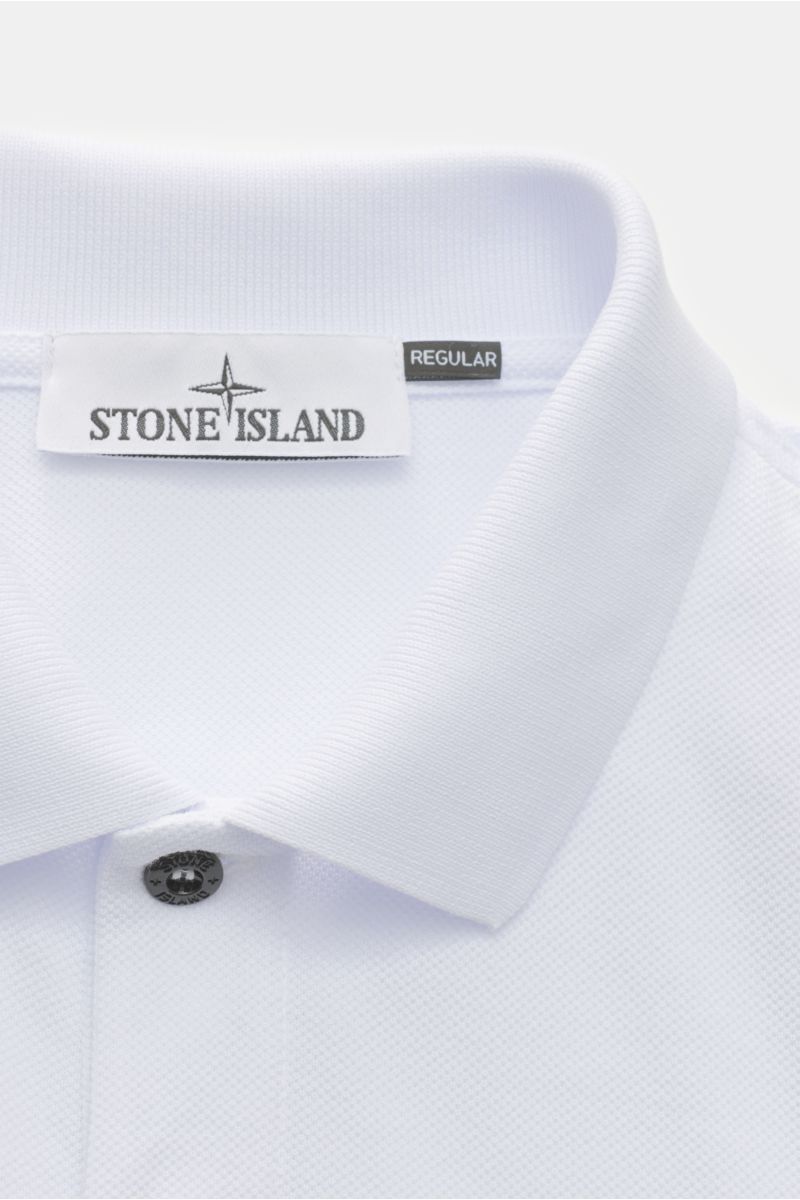 Nahaufnahme des klassischen weißen Stone Island Poloshirts aus Baumwoll-Piqué mit Polokragen, glatter Knopfleiste und Weblabel, frontal fotografiert.
